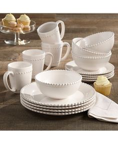 a table topped with white dishes and cupcakes