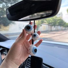 a person holding up two fake eyeballs on a car dash board in front of a rear view mirror