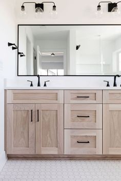 a bathroom with double sinks and large mirror above the vanity area, along with two lights on either side of the sink