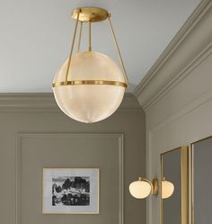 a light fixture hanging from the ceiling in a room with gray walls and gold trim