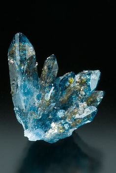 a blue and yellow crystal cluster on a black surface