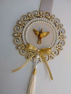 a gold and white brooch with a bird on it's back, hanging from a wall