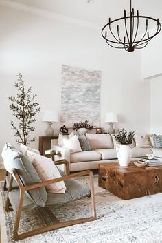 a living room filled with furniture and a chandelier hanging above the couches