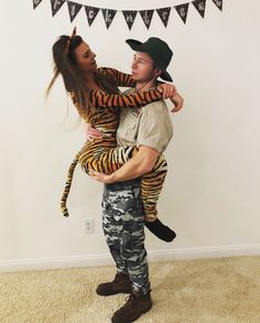 a man holding a woman in his arms while she is dressed up as a tiger