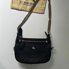 The Bag Has A Strap That Is Convertible From A Crossbody To A Shoulder, Logo Placard At Front, Tonal Canvas Lining, Single Pocket At Interior With Zip Closure, Front Zip Pocket And Zip Closure Top. Purchased At Burberry. This Is Authentic. It’s In Very Good Condition And Used Less Than A Handful Of Times. There Are Very Light Scratches At Hardware, Slight Residue At Interior Pocket. The Size Is Perfect For An Evening Bag Or Day. The Dimensions Are: 9 X6.5 X 2.5 Burberry Black Purse, Burberry Black, Black Pebbles, Burberry Bag, Leather Purse, Chain Strap, Pebbled Leather, Leather Purses, Evening Bags