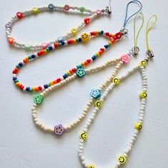 three beaded necklaces with smiley faces and beads on white background, one is multicolored