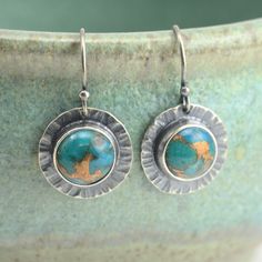 "These all sterling silver earrings feature 8mm blue mohave turquoise cabochons, bezel set against hammered round backplates.  The earrings have been oxidized to highlight the texture. They measure about 1 inch long, including the earwire, and about 1/2 inch wide. To give a sense of the size, a sample was photographed in my hand. You have a choice of earwire styles. Please see the last picture for a comparison of the two style options. Earring measurements listed above are for the ball end earwires (A.); the lever back earwires add about 1/8\" in length.  A. Ball end earwires (shown in earring pictures) (sterling silver,.68mm thick) B. Leverback earwires (sterling silver,.78mm thick) The earrings pictured are the exact ones you will receive  Please read my shipping and policies page on the Turquoise Soldered Sterling Silver Earrings, Hammered Turquoise Sterling Silver Jewelry, Turquoise Hammered Sterling Silver Jewelry, Sterling Silver Patina Earrings, Silversmith Jewelry, Silversmith Jewellery, Earrings Design, Turquoise Earrings, Bezel Setting