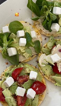 three flatbreads with tomatoes, lettuce and feta cheese on them