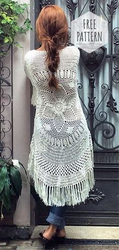 a woman standing in front of a door with her back to the camera, wearing a white crochet dress