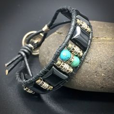 "Mens Turquoise and Onyx beaded leather wrap bracelet in sterling silver with a a dash of Pyrite finished off with a genuine Indian-head Nickel button clasp. Handmade in my home studio in Austin, Texas, U.S.A. I love designing mens jewelry! I always imagine what kind of man will wear it. This bracelet is made of turquoise, onyx, pyrite and sterling silver. The button clasp is made of genuine Indian-head nickel and comes in an Indian Head or Buffalo Head faced The style combines a modern, masculi Artisan Hand Wrapped Black Bracelets, Artisan Hand Wrapped Black Bracelet, Artisan Hand-wrapped Black Bracelet, Adjustable Leather Bracelets With Natural Stones, Bohemian Black Leather Bracelet With Round Beads, Black Bohemian Leather Bracelet With Round Beads, Bohemian Black Bracelets With Polished Beads, Black Bohemian Bracelet With Polished Beads, Bohemian Black Bracelet With Polished Beads