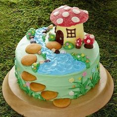 there is a cake that looks like a mushroom house on top of the grass and water