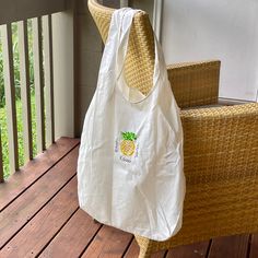 a white bag sitting on top of a wooden porch next to a wicker chair