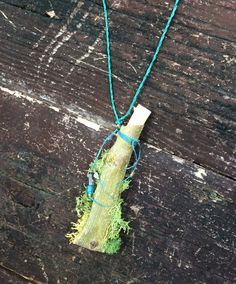 Natural tree bark necklace. Osage Orange (Hedge) bark, peeled from a coppicing tree, which is a fresh shoot from a previously cut tree.  It is folded and rolled, with a natural twig "cork."  Then woven around the top, so the "cork" doesn't come out.  Thread is a teal, or blue green. There is a small amount of preserved bright green moss stuck in at thesides and  bottom!  A few glass and stone beads for sparkle. It is stiff, as it is bark. If you wear it and hug someone hard, you might crush it!   approx. 4" long, including the "cork" about 1 " wide at the widest point flattened at the bottom. Length of string about 37", can be made shorter by tying another knot in the string. Black and white photos of model are of similar (smaller) necklace.  You get the necklace shown in all other photos. Tree Jewelry, Crush It, Natural Tree, Medicine Bag, Small Necklace, Black And White Photos, Amulet Necklace, Jewelry Tree, White Photos