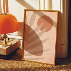 an orange lamp next to a framed photograph on a table