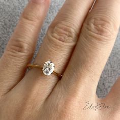 a woman's hand with a diamond ring on top of her finger, showing the center stone