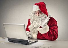 a santa clause sitting in front of a laptop computer