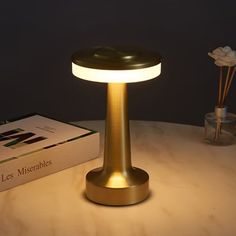 a table with a lamp on it next to a box and some flowers in the background