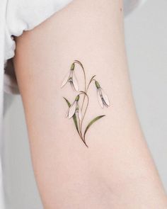 a small flower tattoo on the side of a woman's thigh, with green leaves