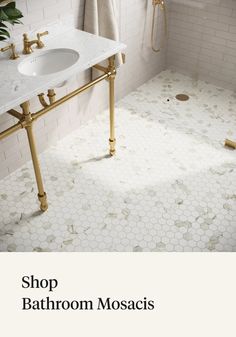 a bathroom with white tile and gold fixtures on the floor, along with an open shower