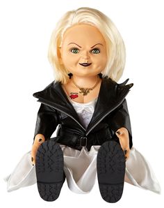 a creepy doll sitting on the ground with her legs crossed and black shoes in front of her