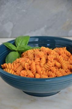 a blue bowl filled with pasta and basil