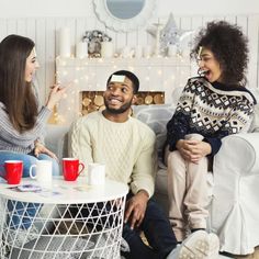 three people sitting on a couch talking to each other and having coffee in front of them