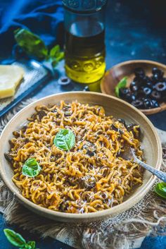 a bowl of pasta with olives and basil