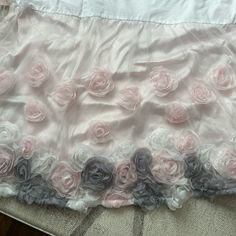 there is a pink and grey flowered skirt on the bed sheet that has ruffled edges