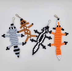 three beaded ornaments are arranged on a white surface, one is orange and the other is black