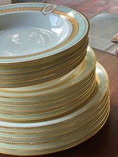 a stack of gold and white plates sitting on top of a wooden table next to a piece of bread