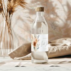 a bottle of water sitting on top of a bed next to a vase with flowers