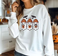 A sturdy and warm sweatshirt bound to keep you warm in the colder months. A pre-shrunk, classic fit sweater that's made with air-jet spun yarn for a soft feel. Cute Coffee Ghosts halloween sweatshirt,halloween shirts,spooky season Cute Coffee Ghosts , Halloween Ghost Design, Cozy Autumn Ghosts, Spooky Coffee , Halloween Sublimation This Cute Coffee Ghosts features a whimsical design of three ghosts enjoying coffee, perfect for adding a cozy and spooky touch to your projects. Whether you're creating t-shirts, mugs, or stickers, this adorable Halloween design is sure to be a hit. Ideal for anyone who loves cute and spooky artwork with an autumn theme.  * 50% cotton, 50% polyester * Pre-shrunk * Classic fit * 1x1 athletic rib knit collar with spandex * Air-jet spun yarn with a soft feel * Dou Halloween Crew Neck Sweater, Spooky Long Sleeve Sweatshirt For Fall, Spooky Long Sleeve Sweatshirt For Winter, Casual Halloween Crew Neck Sweater, Casual Halloween Sweater With Crew Neck, Casual Crew Neck Halloween Sweater, Casual Crew Neck Sweater For Halloween, Halloween Long Sleeve Hoodie With Relaxed Fit, White Crew Neck Sweater For Halloween