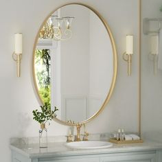 a bathroom with a large round mirror above the sink and a vase on the counter