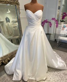 a white wedding dress on display in front of a mirror