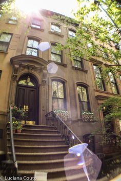 the sun shines brightly in front of an apartment building with stairs and trees on either side