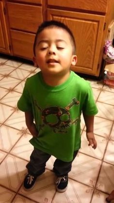 a little boy that is standing up in the kitchen with his eyes closed and mouth wide open