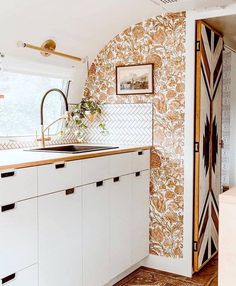 a kitchen with white cabinets and patterned wallpaper on the walls, along with a sink