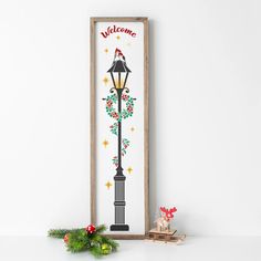 a wooden sign with a lamp post and christmas decorations next to it on a white wall