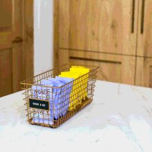 a basket filled with boxes sitting on top of a white counter next to wooden cabinets