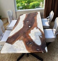 a dining room table with white chairs and a large slab of wood on the top