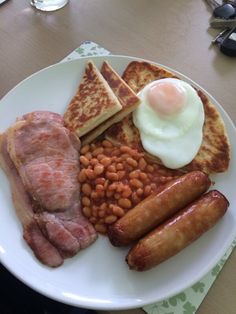 a white plate topped with breakfast foods on top of a table