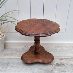 a small wooden table sitting on top of a floor next to a potted plant