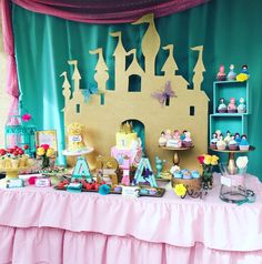 a table topped with cakes and cupcakes next to a wall covered in curtains