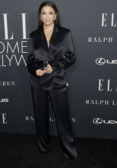 an image of a woman posing for the camera on the red carpet in a black suit