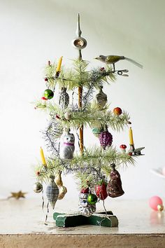 a small christmas tree with ornaments hanging from it's branches and birds on top