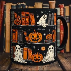 a black coffee mug decorated with halloween books and pumpkins