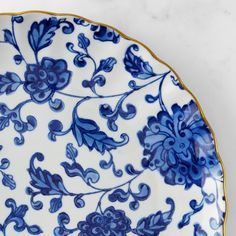 an ornate blue and white plate with gold trimmings on the edge, sitting on a marble surface