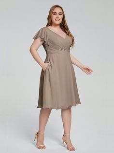 a woman in a brown dress posing for the camera with her hands on her hips