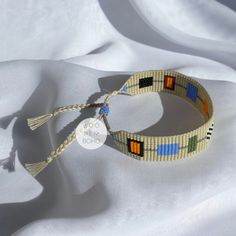 the bracelet is made with multicolored beads and tassels on white fabric