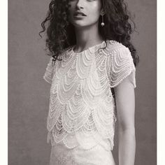 a black and white photo of a woman with curly hair wearing a dress made of beads